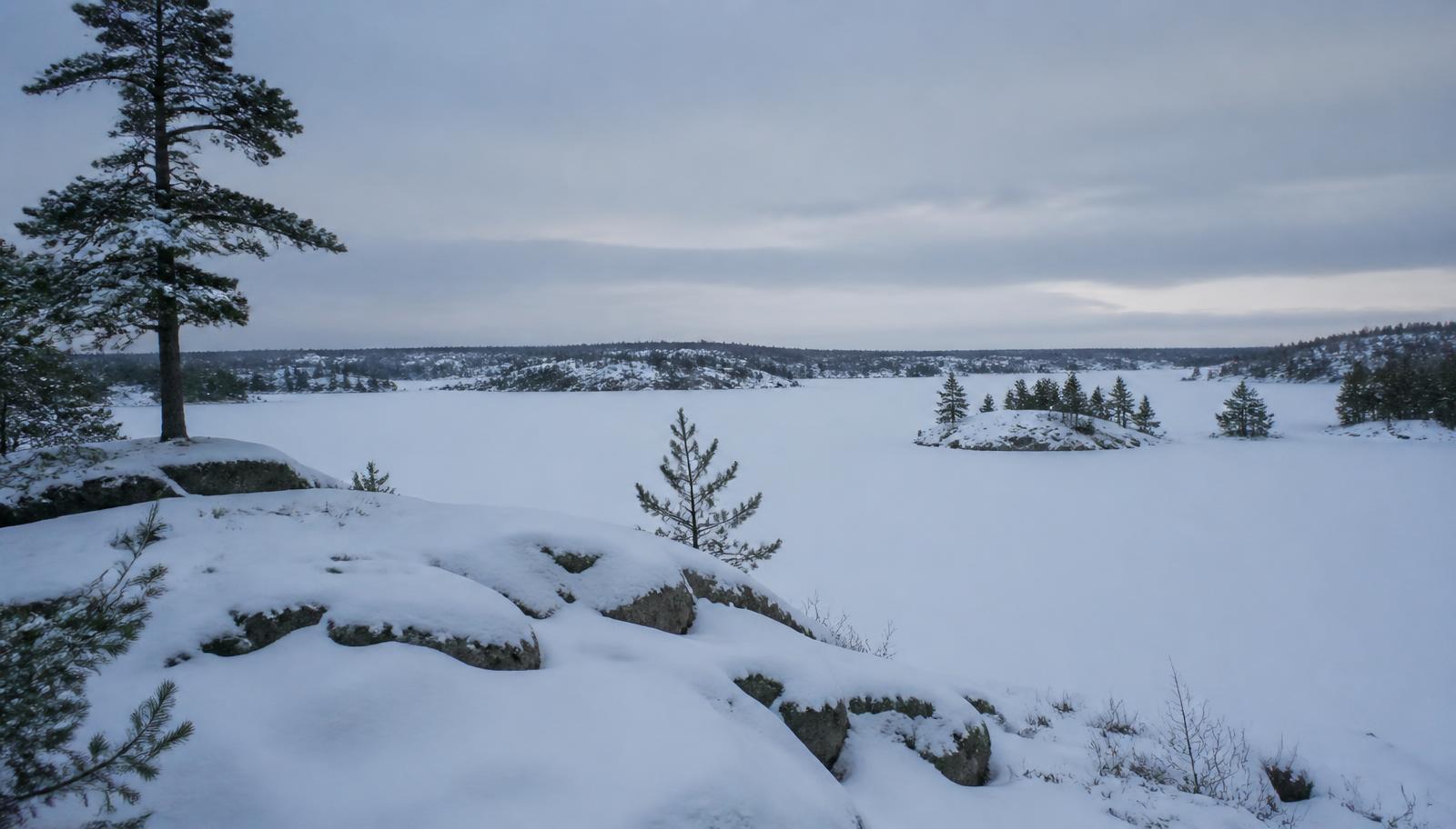 Wide Canadian Shield lake country under snow, rock ridges and evergreens in winter light.